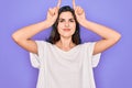 Young beautiful brunette woman wearing casual white t-shirt over purple background doing funny gesture with finger over head as Royalty Free Stock Photo