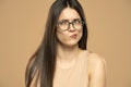 Young beautiful brunette woman wearing casual yellow shirt and glasses, posing over beige background Thinking concentrated about Royalty Free Stock Photo