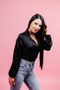 Young beautiful brunette woman wearing classic black shirt and jeans over  pink background looking away to side with smile Royalty Free Stock Photo