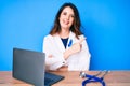 Young beautiful brunette woman wearing doctor uniform with blue ribbon smiling cheerful pointing with hand and finger up to the Royalty Free Stock Photo