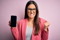 Young beautiful brunette woman wearing glasses holding smartphone showing screen annoyed and frustrated shouting with anger, crazy Royalty Free Stock Photo