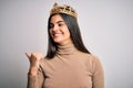 Young beautiful brunette woman wearing golden queen crown over isolated white background smiling with happy face looking and Royalty Free Stock Photo