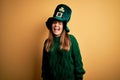 Young beautiful brunette woman wearing green hat on st patricks day celebration winking looking at the camera with sexy