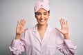 Young beautiful brunette woman wearing pajama and sleep mask over white background showing and pointing up with fingers number ten Royalty Free Stock Photo