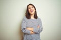 Young beautiful brunette woman wearing striped sweater over white isolated background happy face smiling with crossed arms looking Royalty Free Stock Photo