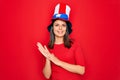 Young beautiful brunette woman wearing united states hat celebrating independence day clapping and applauding happy and joyful,