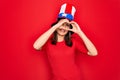 Young beautiful brunette woman wearing united states hat celebrating independence day Doing heart shape with hand and fingers