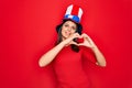 Young beautiful brunette woman wearing united states hat celebrating independence day smiling in love doing heart symbol shape