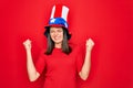 Young beautiful brunette woman wearing united states hat celebrating independence day very happy and excited doing winner gesture