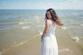 Young beautiful brunette woman in white dress on the seashore. Back view Royalty Free Stock Photo