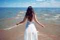 Young beautiful brunette woman in white dress on the seashore. Royalty Free Stock Photo