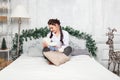 Young beautiful brunette woman in a white shirt and blue jeans sits on the bed and looking to the teddy bear toy like on baby in Royalty Free Stock Photo