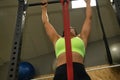 Young, beautiful, brunette woman in yellow top and black leggings, doing pull-up exercises on a bar in gym. Fitness concept, Royalty Free Stock Photo