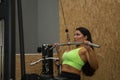 Young, beautiful, brunette woman, with yellow top and black tights, doing chest pull-ups for dorsal exercises at the gym. Fitness Royalty Free Stock Photo