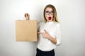 Young beautiful business woman in eyeglasses holding awaited lunch in paper bag from food delivery service pointing with Royalty Free Stock Photo