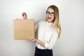 Young beautiful business woman in eyeglasses holding awaited lunch in paper craft bag from food delivery service Royalty Free Stock Photo