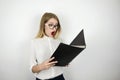 Young beautiful business woman in eyeglasses looking surprised at black folder with documents isolated white background Royalty Free Stock Photo