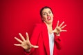 Young beautiful business woman standing over red isolated background afraid and terrified with fear expression stop gesture with Royalty Free Stock Photo