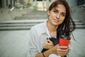 Beautiful business woman is going to work with coffee walking near office buildings. Portrait of a successful business woman holdi Royalty Free Stock Photo