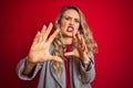 Young beautiful business woman wearing elegant jacket standing over red isolated background afraid and terrified with fear Royalty Free Stock Photo