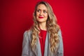 Young beautiful business woman wearing elegant jacket standing over red isolated background smiling looking to the side and Royalty Free Stock Photo