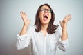 Young beautiful business woman wearing glasses over isolated background celebrating mad and crazy for success with arms raised and Royalty Free Stock Photo