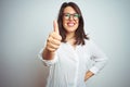 Young beautiful business woman wearing glasses over isolated background doing happy thumbs up gesture with hand Royalty Free Stock Photo