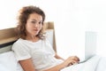 Young beautiful business woman working with laptop while lying in bed in the morning after waking up Royalty Free Stock Photo