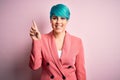 Young beautiful businesswoman with blue fashion hair wearing jacket over pink background showing and pointing up with finger Royalty Free Stock Photo