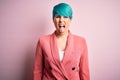 Young beautiful businesswoman with blue fashion hair wearing jacket over pink background sticking tongue out happy with funny Royalty Free Stock Photo