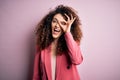 Young beautiful businesswoman with curly hair and piercing wearing elegant jacket doing ok gesture with hand smiling, eye looking Royalty Free Stock Photo