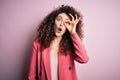 Young beautiful businesswoman with curly hair and piercing wearing elegant jacket doing ok gesture shocked with surprised face, Royalty Free Stock Photo