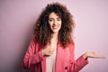 Young beautiful businesswoman with curly hair and piercing wearing elegant jacket Showing palm hand and doing ok gesture with Royalty Free Stock Photo