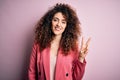 Young beautiful businesswoman with curly hair and piercing wearing elegant jacket smiling looking to the camera showing fingers Royalty Free Stock Photo