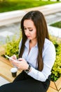 Young beautiful businesswoman drinks coffee and use cellphone