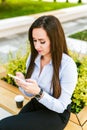 Young beautiful businesswoman drinks coffee and use cellphone