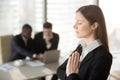 Young beautiful businesswoman enjoys meditating in office with e Royalty Free Stock Photo