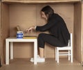 Young beautiful businesswoman sits in office cardboard box and works fiercely