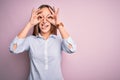 Young beautiful businesswoman wearing elegant shirt standing over isolated pink background doing ok gesture like binoculars Royalty Free Stock Photo