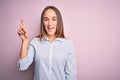 Young beautiful businesswoman wearing elegant shirt standing over isolated pink background showing and pointing up with finger Royalty Free Stock Photo