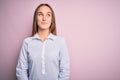 Young beautiful businesswoman wearing elegant shirt standing over isolated pink background smiling looking to the side and staring Royalty Free Stock Photo
