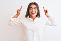 Young beautiful businesswoman wearing glasses standing over isolated white background smiling amazed and surprised and pointing up Royalty Free Stock Photo