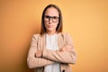 Young beautiful businesswoman wearing jacket and glasses over isolated yellow background skeptic and nervous, disapproving Royalty Free Stock Photo