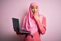 Young beautiful businesswoman wearing pink muslim hijab and business jacket using laptop cover mouth with hand shocked with shame Royalty Free Stock Photo