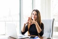 Young beautiful businesswoman working on laptop and keeping hand on chin while sitting at her working place Royalty Free Stock Photo