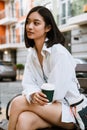 Young beautiful calm asian woman with coffee looking aside