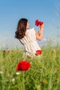 Young beautiful calm girl dreaming on a poppy field, summer outdoor.