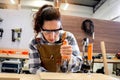 Young beautiful carpenter woman wearing safety glasses goggles and apron, using carpentry tools with wood plank to make wooden Royalty Free Stock Photo