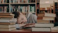 Young beautiful caucasian female student is sleeping on table surrounded by piles of books and papers, phone is lieing Royalty Free Stock Photo