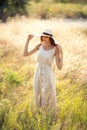 young beautiful female walks on field in summer while wearing a sunhat and midi dress. Lifestyle